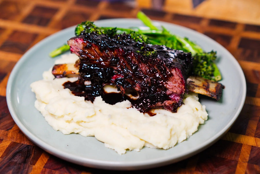 Cherry Dr Pepper bourbon beef short ribs served over mashed potatoes with broccolini